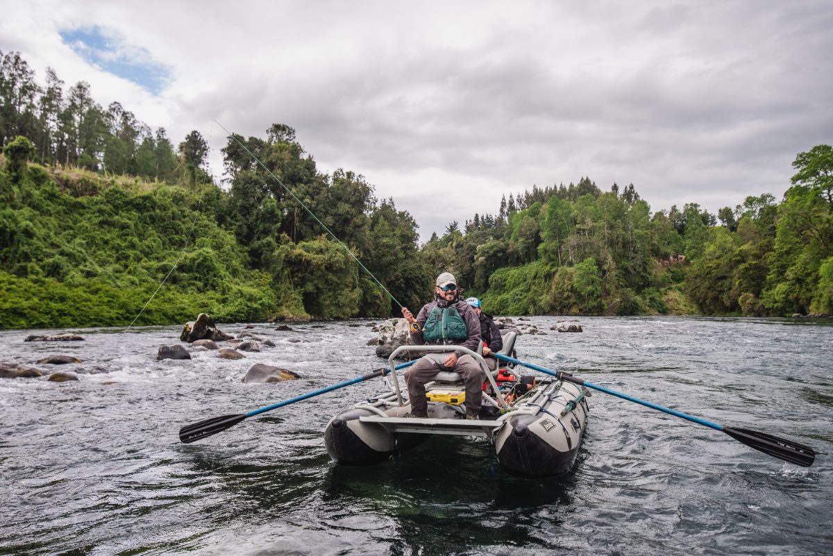 Guía de pesca lanzando desde un bote inflable en un río de Los Ríos